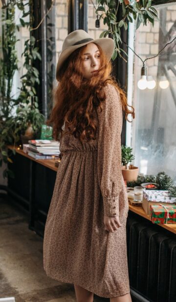 woman in long sleeve dress standing near glass window