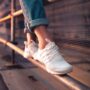 person in blue jeans and white sneakers standing on metal railings